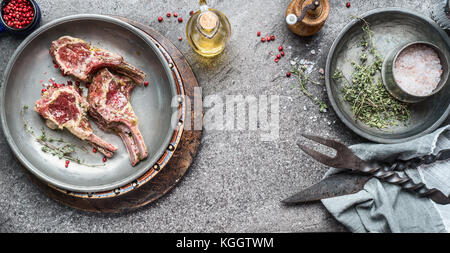 Materie marinata di costolette di agnello barbecue per la cottura alla griglia o la frittura con l'olio e le erbe aromatiche, vista dall'alto, spazio di copia Foto Stock