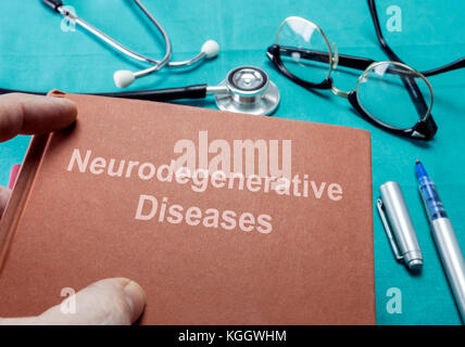 Medico detiene il libro su malattie neurodegenerative in un ospedale Foto Stock