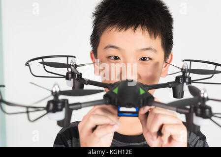 Ragazzo asiatico che tiene il drone o il quadricottero in mano, studio girato su sfondo bianco. Foto Stock