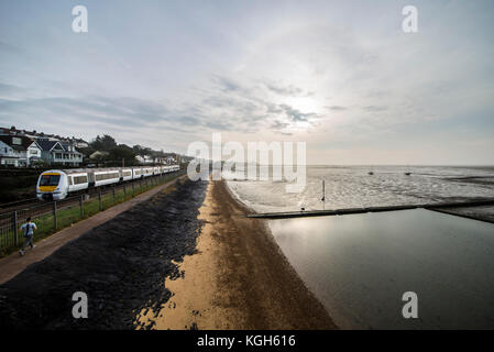 C2c classe Trenitalia 357 convoglio ferroviario passando seawall estuario del Tamigi a Chalkwell, Southend on Sea la mattina presto. Spiaggia. Pareggiatore. Barche. Piscina Foto Stock