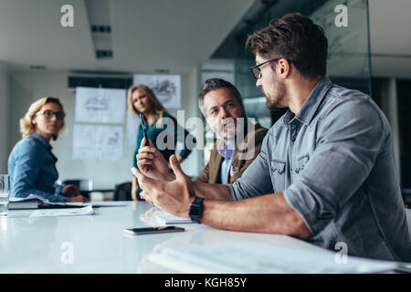 Imprenditore di presentare i suoi suggerimenti ai colleghi. Startup business team sulla riunione di moderno luminoso ufficio. Foto Stock