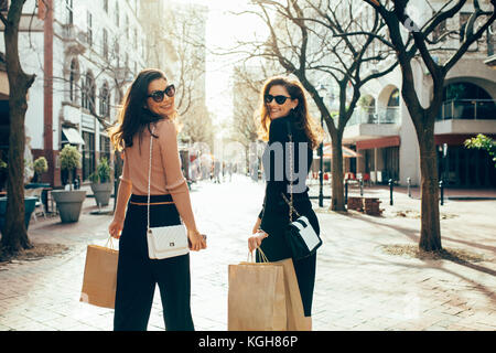 Due amiche per divertirsi a fare shopping in città. Le donne con le borse della spesa camminando sulla strada della citta'. Foto Stock