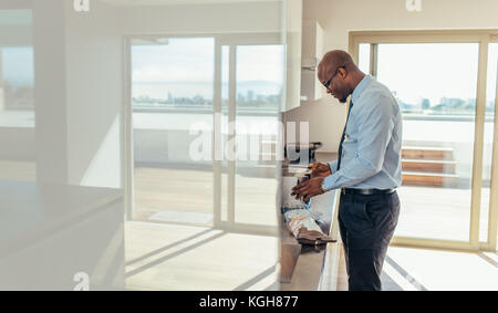 Un uomo vestito di formali che preparava la colazione in cucina. uomo d'affari che usa il forno per preparare la colazione. Foto Stock
