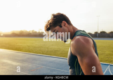 Primo piano di un velocista in piedi su una via di corsa. Atleta guardando giù presso la pista. Foto Stock