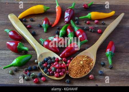 Molto caldo il personale in cucina appena prelevato il rosso, il verde e il giallo di peperoncino e due cucchiai di legno pieno di nero e rosso pepe e peperoncino essiccato Foto Stock