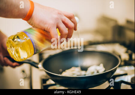 Lo chef versa l'olio nella padella in cucina del ristorante Foto Stock