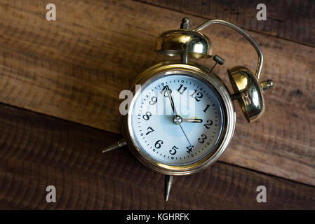 Golden time clock - golden bell orologio su una tavola di legno sfondo Foto Stock