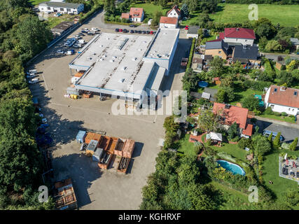 Grande capannone industriale accanto a una zona residenziale con ville e giardini, vista aerea con drone Foto Stock