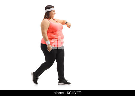 Lunghezza piena ripresa del profilo di una donna sovrappeso camminare e controllare il suo orologio sportivo isolati su sfondo bianco Foto Stock