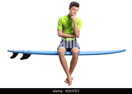 Malinconici teen surfer seduto su di una tavola da surf isolati su sfondo bianco Foto Stock