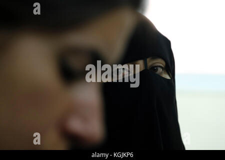 Una donna beduina che indossa un niqab o un niqaab guardando una donna beduina secolare nella città di Beerseba sud Israele Foto Stock