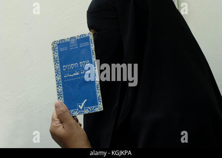 Una donna beduina che indossa un niqab o niqaab tiene il suo libretto di vaccinazione nella città di Beerseba sud Israele Foto Stock