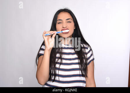 Close-up donna spazzolare i suoi denti isolati a sfondo bianco. Foto Stock