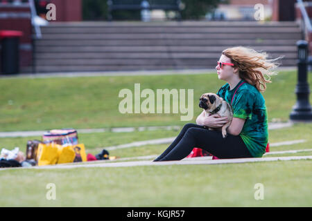 Suwanee GA, Stati Uniti d'America - 6 Maggio 2017: una giovane donna amorevolmente mantiene la sua pug cane mentre è seduto sull'erba a Woofstock, un cane festival a Suwanee Town Ctr. Foto Stock