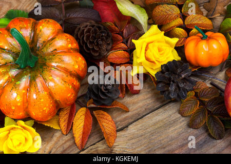 Ringraziamento arancione zucca, pigne e giallo rose sfondo rustico, close up Foto Stock