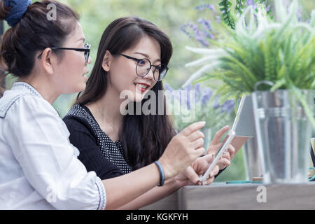 La relazione di due giovani donna asiatica parlando con smart phone in mano la felicità volto sorridente Foto Stock