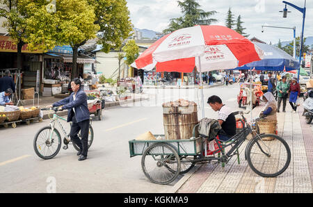 Lijiang, Yunnan, Cina - 28 Settembre 2017: fornitore di prodotti alimentari attende i clienti con una bicicletta in stallo su una strada di Lijiang. Foto Stock