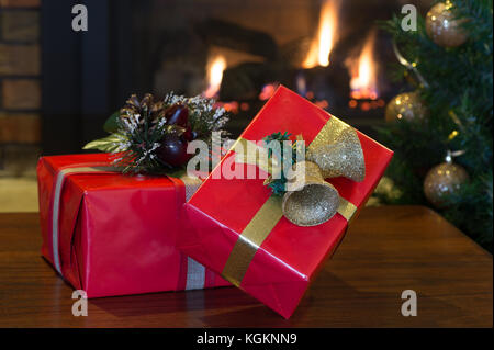 Due red regali di Natale con albero e camino in background Foto Stock