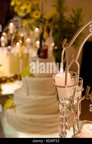 Dettaglio di tutto il tavolo di nozze decorato con candele appesi e fiori e torta sullo sfondo Foto Stock