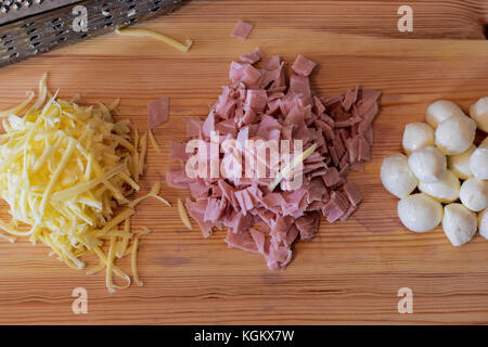 Il formaggio grattugiato e il prosciutto tritato, palline di mozzarella e grattugia su sfondo di legno Foto Stock