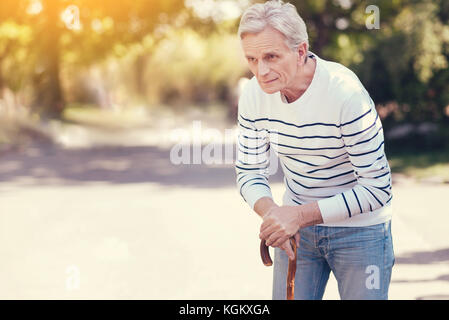 Piacevole uomo senior usando un bastone da passeggio Foto Stock