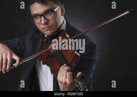 Uomo bello indossare formali suona il violino su sfondo nero Foto Stock