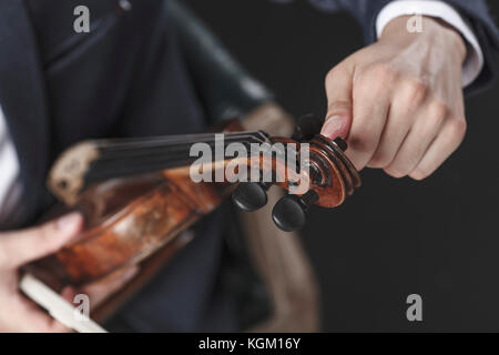 Immagine ritagliata del musicista tuning Violin strings Foto Stock