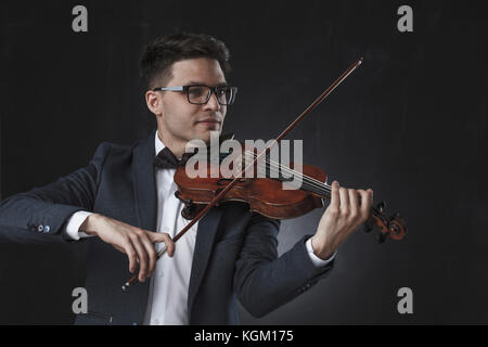 Sorridente bello il violinista suona il violino su sfondo nero Foto Stock