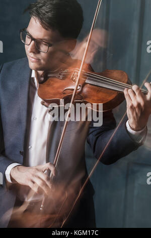 Moto sfocata del bel giovane suona il violino con gli occhi chiusi Foto Stock