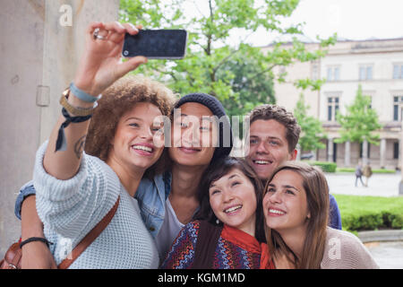 Sorridente giovane donna prendendo selfie con multi-etnico amici, Berlino, Germania Foto Stock