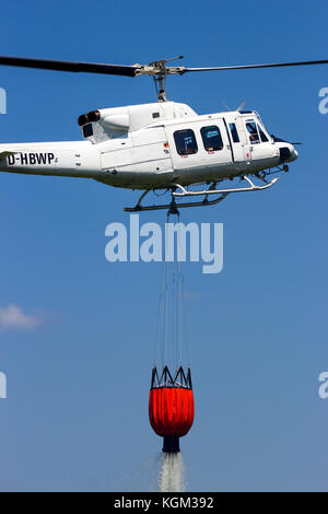 Ahlen, Germania - 5 GIU 2016: campana 212 elicottero con un secchio di acqua utilizzata per la boccola dell'antenna per la lotta antincendio. Foto Stock