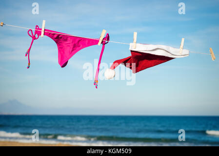 Tanga Bikini e santa hat essiccazione su una spiaggia soleggiata, una fuga stagionale concept Foto Stock