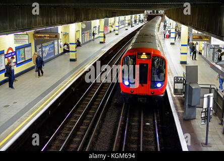 Un treno della metropolitana presso la piattaforma della stazione di Aldgate East sulla metropolitana di Londra con i pendolari in attesa Foto Stock
