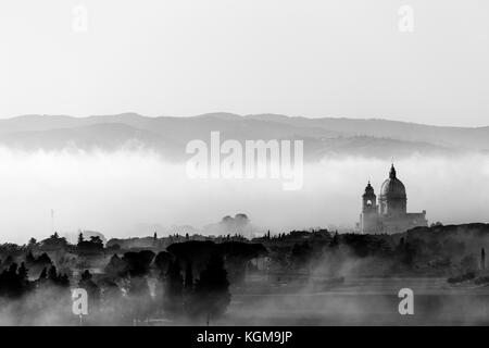 Vista su Santa Maria degli Angeli chiesa papale (Assisi) contro uno sfondo di nebbia all'alba Foto Stock