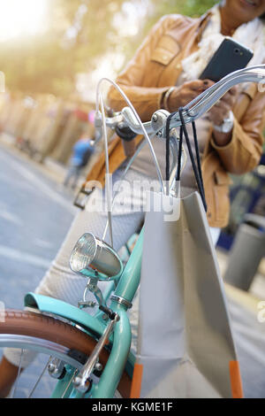 Senior donna utilizzando la bici in giornata di acquisti Foto Stock