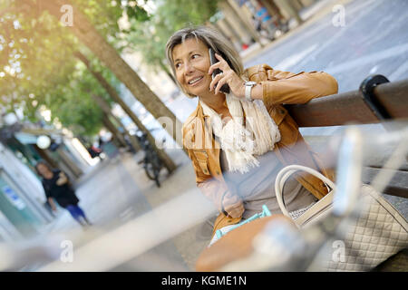 Senior donna utilizzando la bici in giornata di acquisti Foto Stock