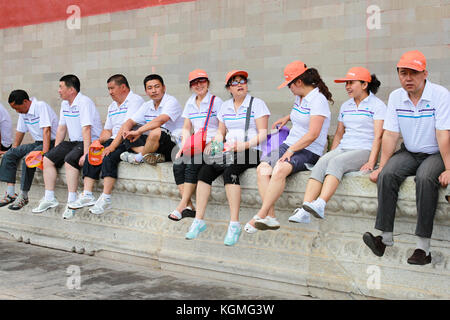 Turisti asiatici seduto e assunzione di rottura su un muro basso in città proibita, il museo del palazzo, a nord di piazza Tiananmen. Pechino, 18.giugno 2010 Foto Stock