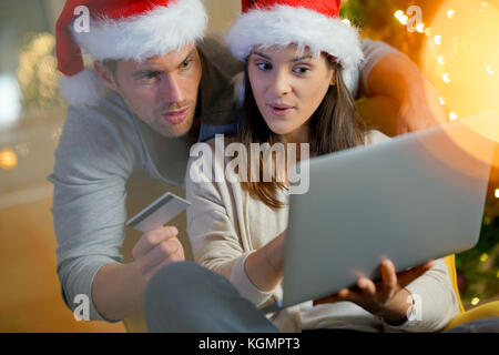 Giovane comprare regali di Natale online con laptop Foto Stock
