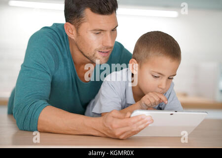 L'uomo con i bambini collegati su tavoletta digitale in casa Foto Stock