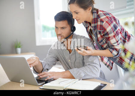 Workteam in ufficio a lavorare insieme su laptop Foto Stock