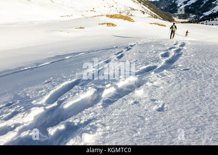 Footsprints nella neve. Due persone in esecuzione in discesa attraverso la neve profonda con snoeshoes. Foto Stock