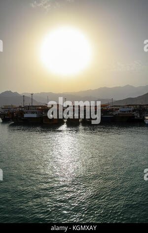 Vista su una barca ormeggiata al porticciolo di Oman, splendido tramonto sulle montagne al Hajar Foto Stock