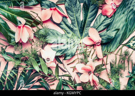 Layout creativo fatto di fiori tropicali e foglie di palmo sul rosa pastello sfondo, vista dall'alto, laici piatta Foto Stock