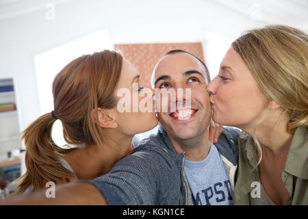 Allegro ragazzo di scattare la foto delle ragazze baciare lui Foto Stock