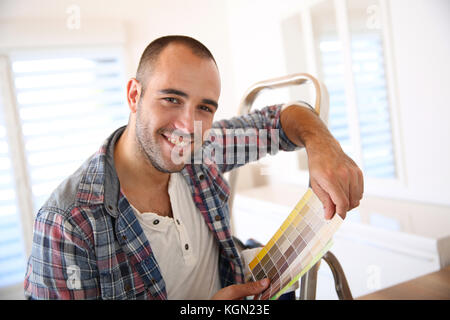 Allegro ragazzo nel nuovo appartamento cercando i colori di vernice Foto Stock