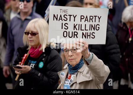 Brutto uccisione di partito targhetta NHS durante il nostro NHS manifestazione di protesta rally marzo contro le presunte UK Tory tagli conservatore e piani di privatizzazione Foto Stock