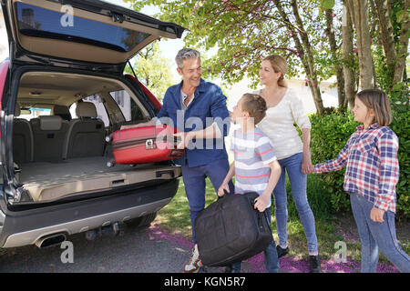 La famiglia felice carico dei bagagli nel veicolo Foto Stock