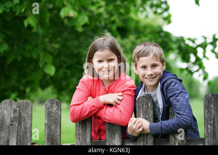 Ritratto di arrampicata per bambini sulla recinzione in campagna Foto Stock