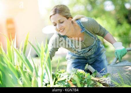 Sorridente donna bionda giardinaggio Foto Stock