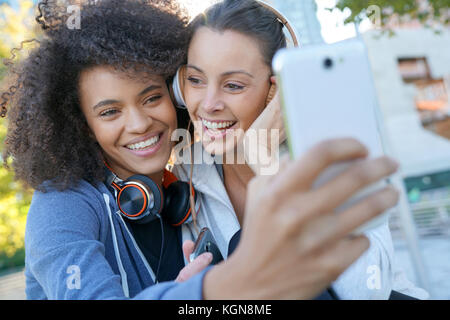 Ragazze in abito sportivo per ascoltare musica sullo smartphone Foto Stock